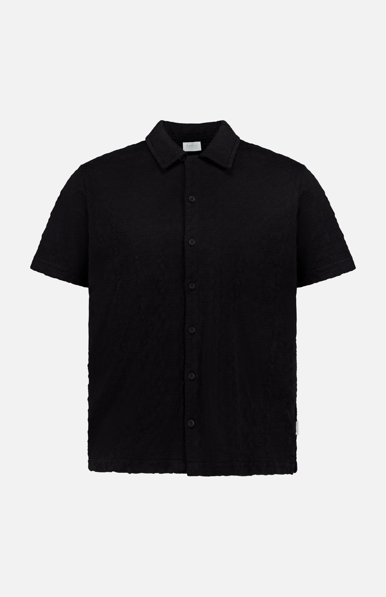 The Abstract Jersey Cuba Shirt by 04651/ A TRIP IN A BAG is a lightweight cotton, short-sleeve, button-up black shirt with a classic Cuban collar, shown against a plain white background.