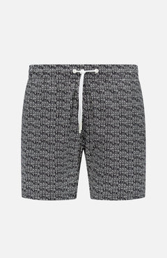 The Abstract Swim Trunk by 04651/ A TRIP IN A BAG features a black and white abstract print and a white drawstring waist, shown on a plain white background—ideal standout men’s beachwear.