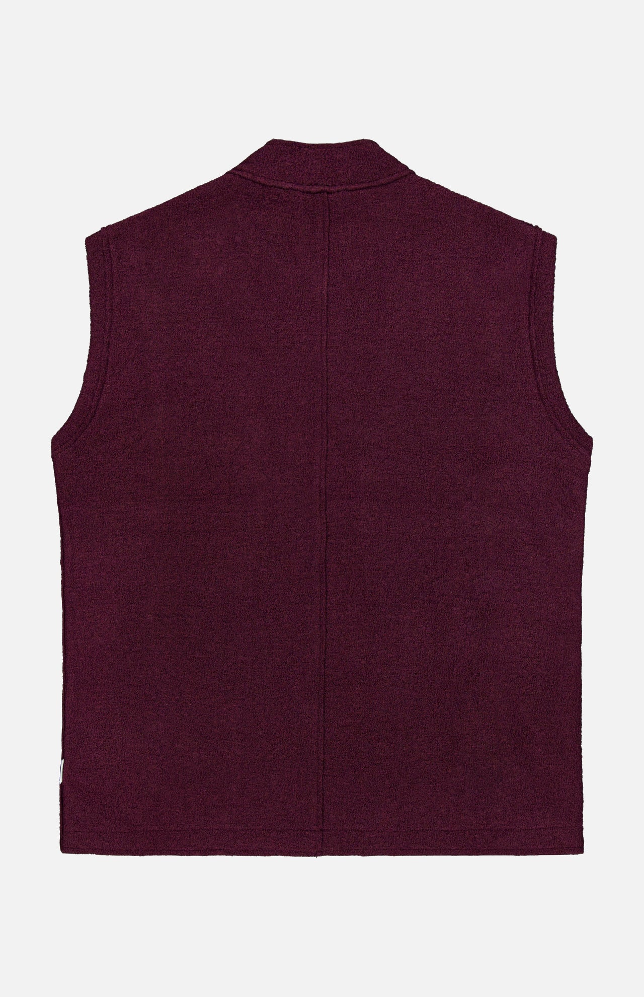 The Boiled Virgin Wool Vest by 04651/ A TRIP IN A BAG is shown from the back in a rich wine tone, featuring a sleeveless design, straight hem, and minimal detailing, set against a plain white background.