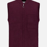 A sleeveless Boiled Virgin Wool Vest by 04651/ A TRIP IN A BAG, in a wine tone, crafted from soft fleece, featuring a front zipper and a single chest pocket, displayed on a plain white background.