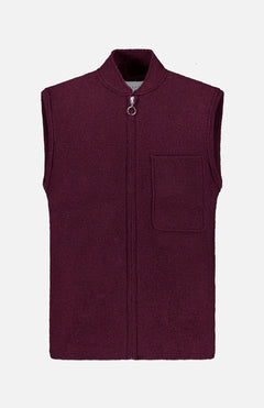 A sleeveless Boiled Virgin Wool Vest by 04651/ A TRIP IN A BAG, in a wine tone, crafted from soft fleece, featuring a front zipper and a single chest pocket, displayed on a plain white background.