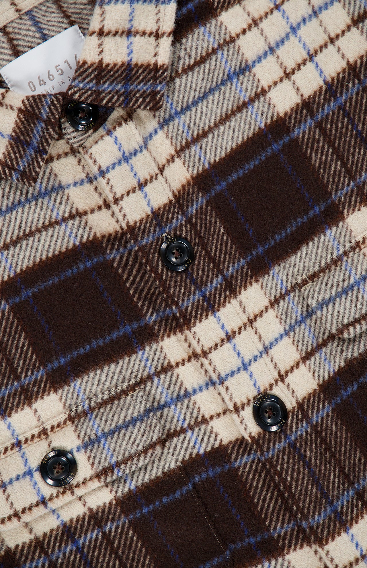 Close-up of a brown, cream, and blue 04651/ A TRIP IN A BAG Checkered Overshirt.