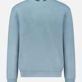 The Cotton Linen Crewneck Sweatshirt by 04651/ A TRIP IN A BAG is a light blue, long-sleeve crewneck with ribbed cuffs and waistband, made from organic cotton, shown on a white background.