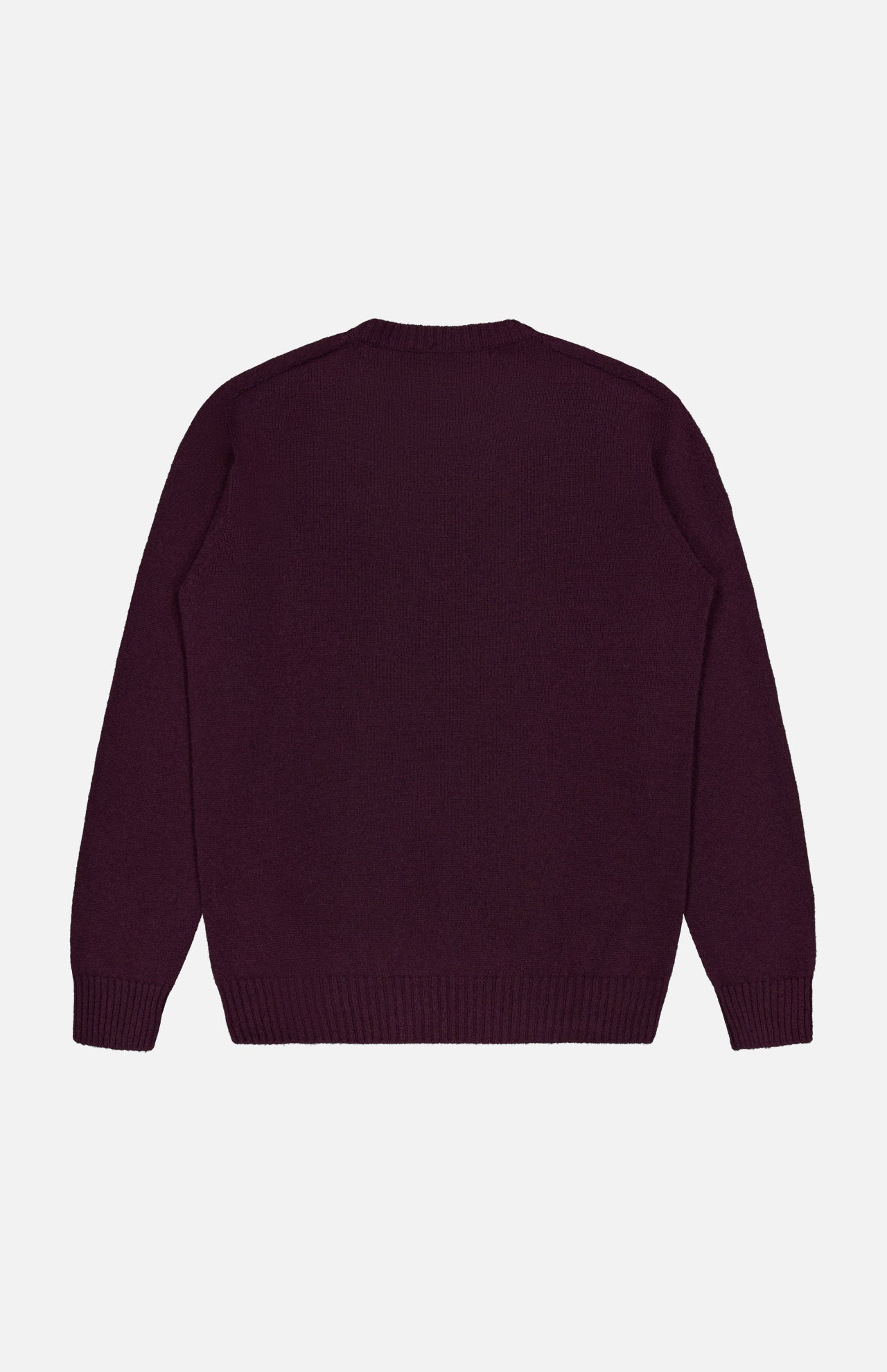 The Extreme Cashmere Crewneck Sweater by 04651/ A TRIP IN A BAG, a plain long-sleeved dark purple cashmere piece with a crew neck, is laid flat with the back facing up against a white background.