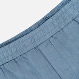 Close-up of the waistband and upper section of the Linen Bermuda Short by 04651/ A TRIP IN A BAG, crafted in Portugal from light blue linen. Features an elastic waist and visible stitching for a soft, lightweight, comfortable fit.