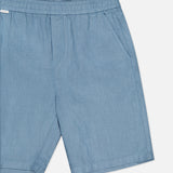 The Linen Bermuda Short by 04651/ A TRIP IN A BAG features light blue linen, an elastic waistband, and side pockets. Made in Portugal, it is displayed on a plain white background.