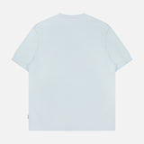 The TP T-shirt by 04651/ A TRIP IN A BAG is shown laid flat with the back visible on a white background. This light blue, pure cotton tee is casual and plain, featuring no visible logos, patterns, or designs.