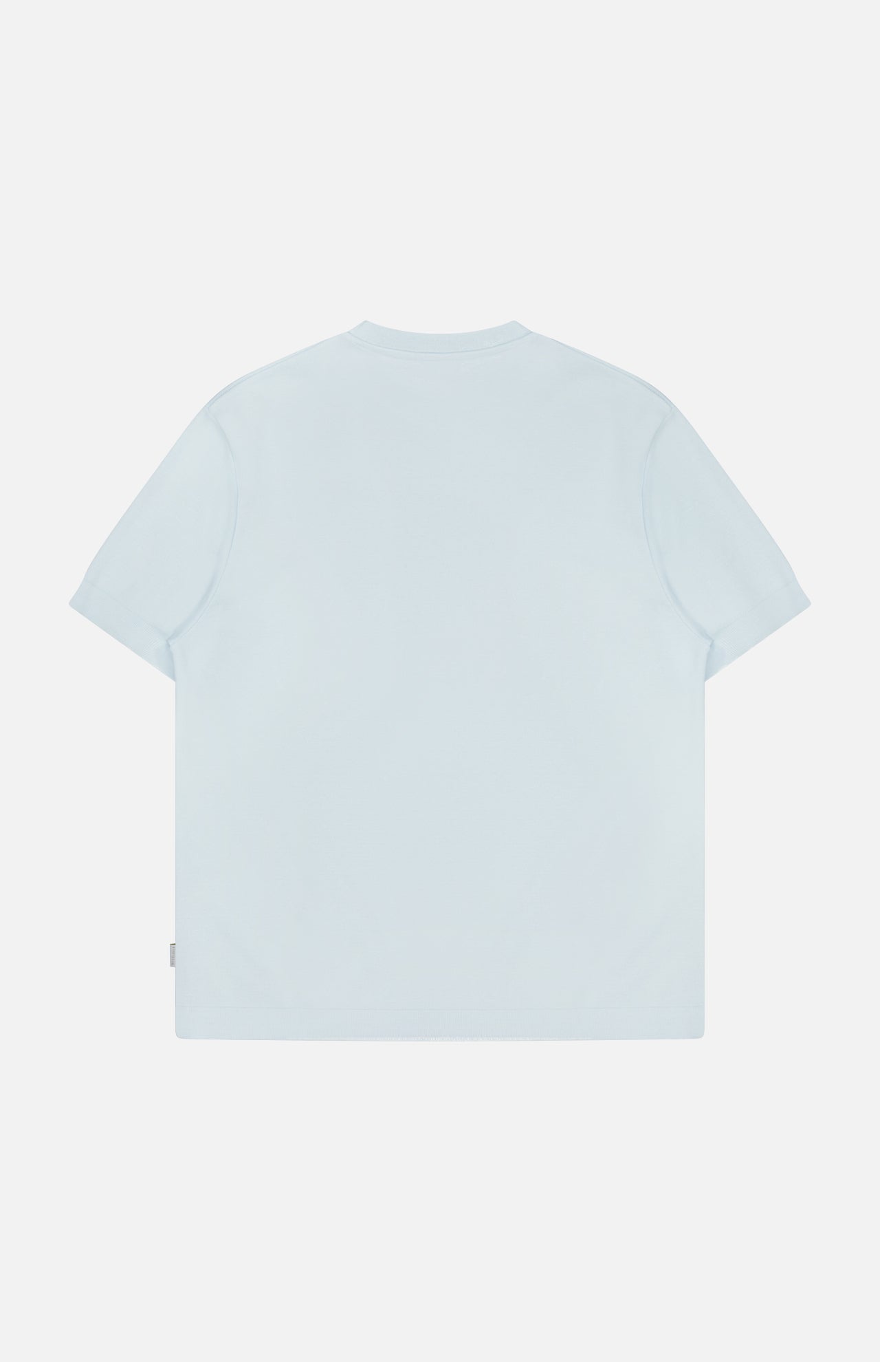The TP T-shirt by 04651/ A TRIP IN A BAG is shown laid flat with the back visible on a white background. This light blue, pure cotton tee is casual and plain, featuring no visible logos, patterns, or designs.