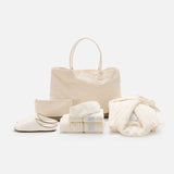 The Voyage Set Tote Bag by 04651/ A TRIP IN A BAG, along with a matching zip pouch, folded towels, cozy slippers, and a folded waffle robe tied with a bow, are arranged neatly on a white background.