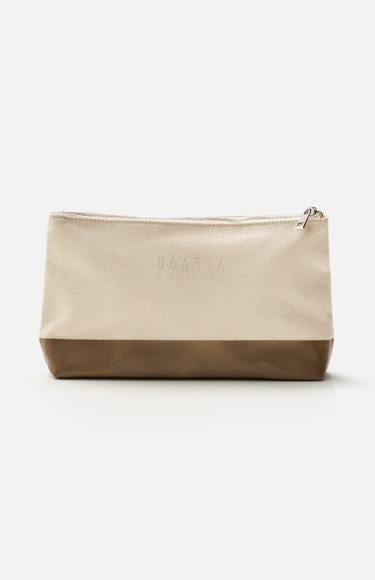 A beige zippered pouch with a brown base, photographed against a white background, features the subtle 04651/ A TRIP IN A BAG branding embossed on the upper front—an understated accessory from the Voyage Set Tote Bag collection, ideal for organizing small essentials in your travel tote.