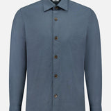 The 100 HANDS Seersucker Dress Shirt is a blue, long-sleeved shirt with a textured finish, collar, and brown buttons, handmade in India and shown against a plain white background.
