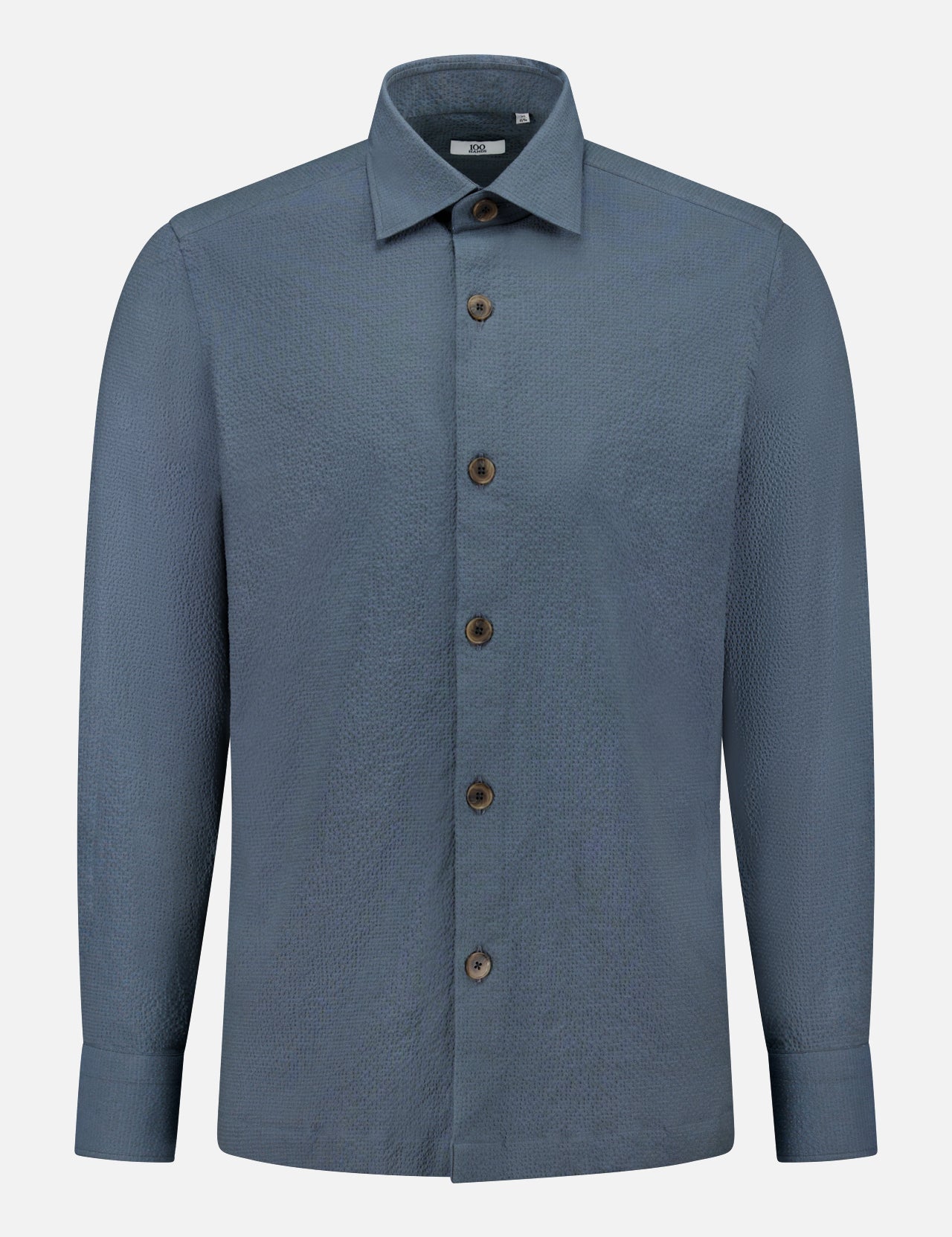 The 100 HANDS Seersucker Dress Shirt is a blue, long-sleeved shirt with a textured finish, collar, and brown buttons, handmade in India and shown against a plain white background.