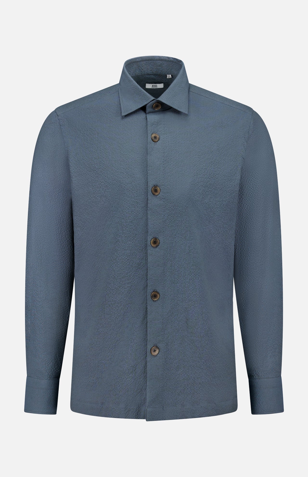 The 100 HANDS Seersucker Dress Shirt is a blue, long-sleeved shirt with a textured finish, collar, and brown buttons, handmade in India and shown against a plain white background.
