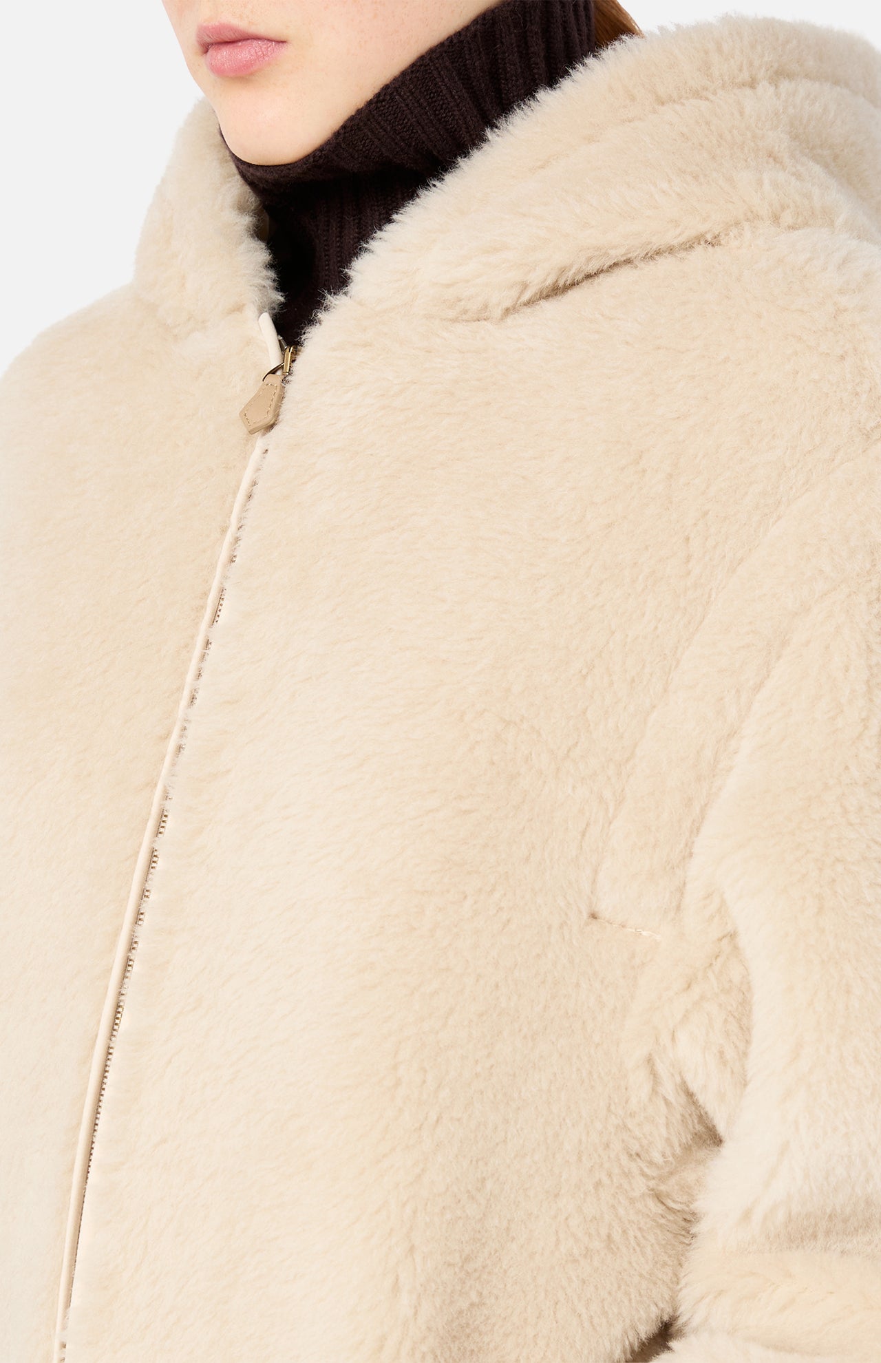 A person wears a beige Max Mara Teddy Hooded Coat made of textured material.