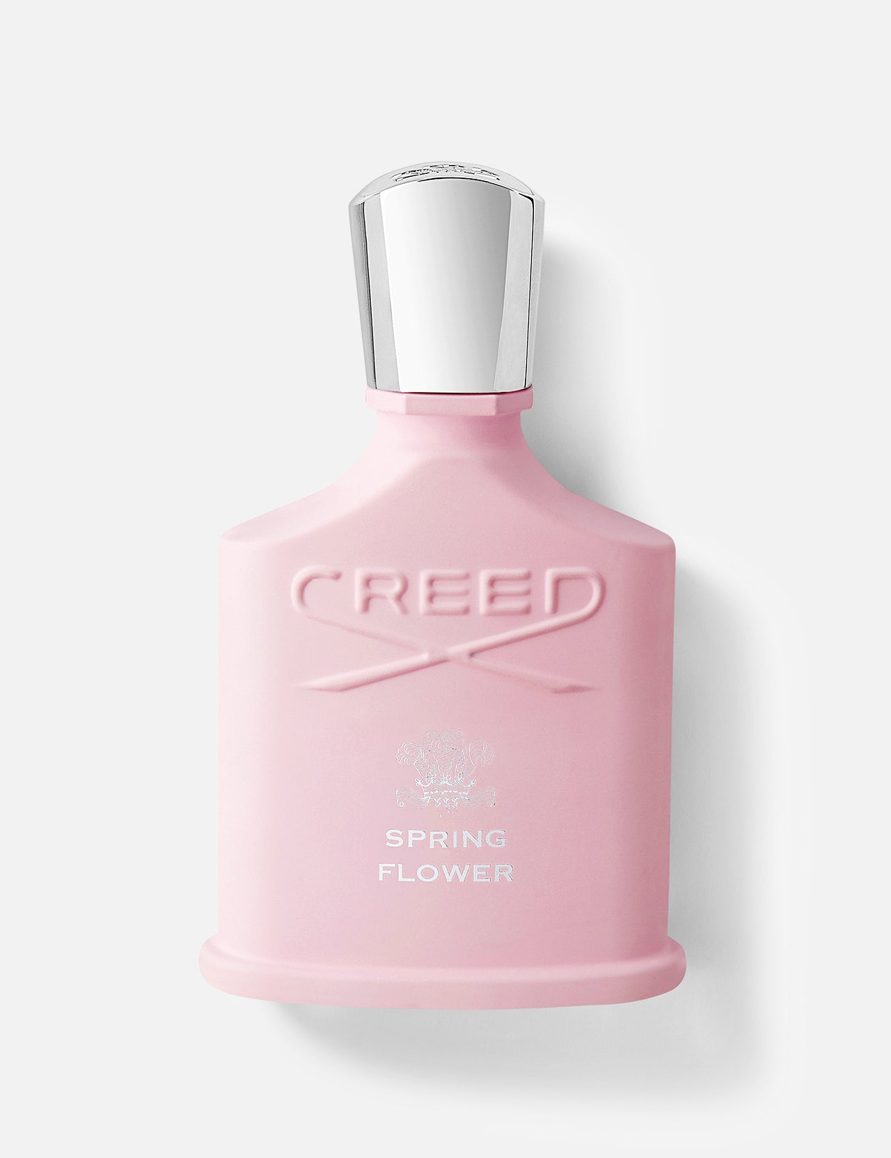 A pink CREED Spring Flower perfume bottle with a silver cap and white label stands against a plain light background, echoing the feminine elegance of Hollywood’s Golden Age.