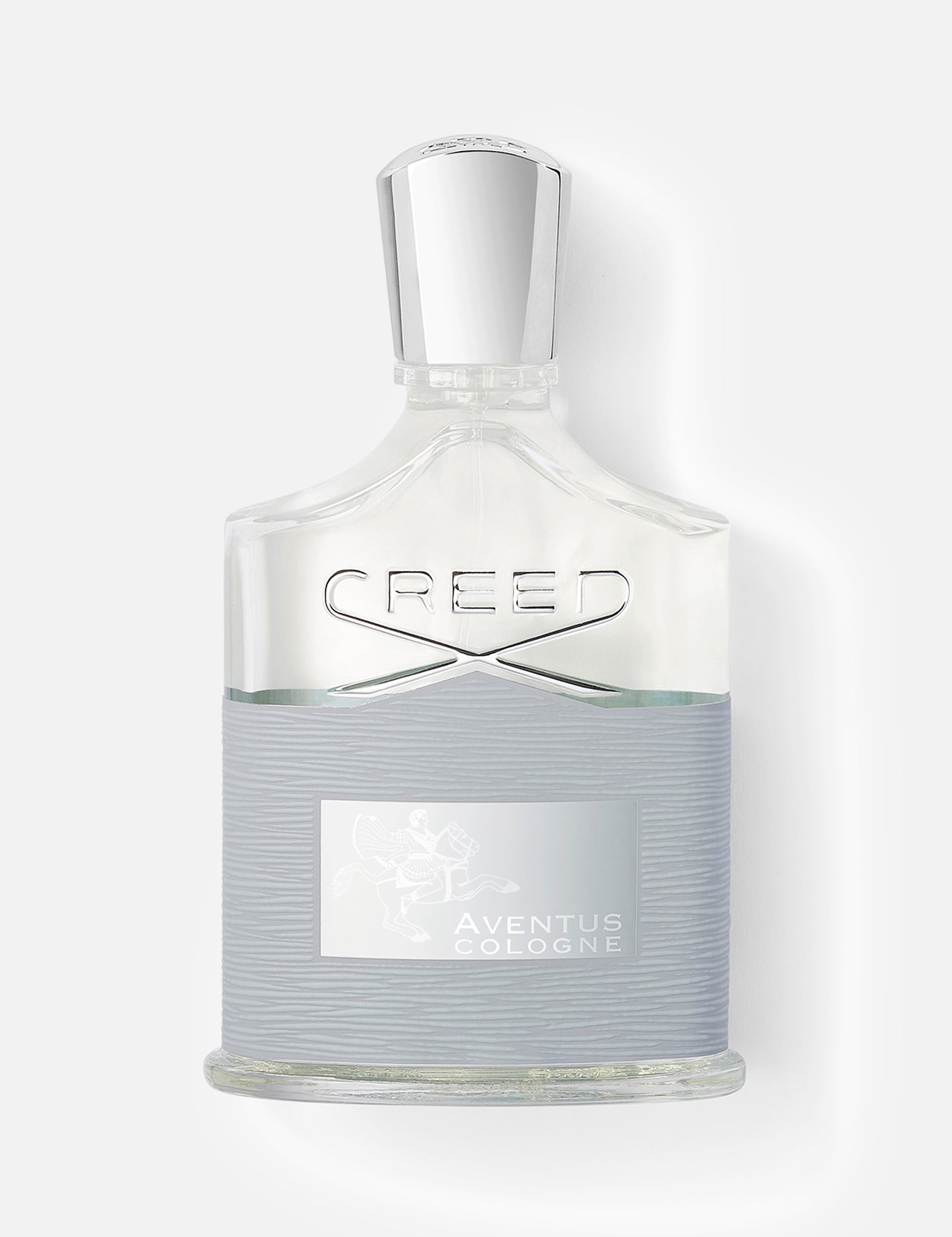 A 100 ml clear glass bottle of CREED Aventus Cologne with a silver cap and textured gray label, displaying the brand name and logo on white—a woody fresh fragrance in an elegant design.