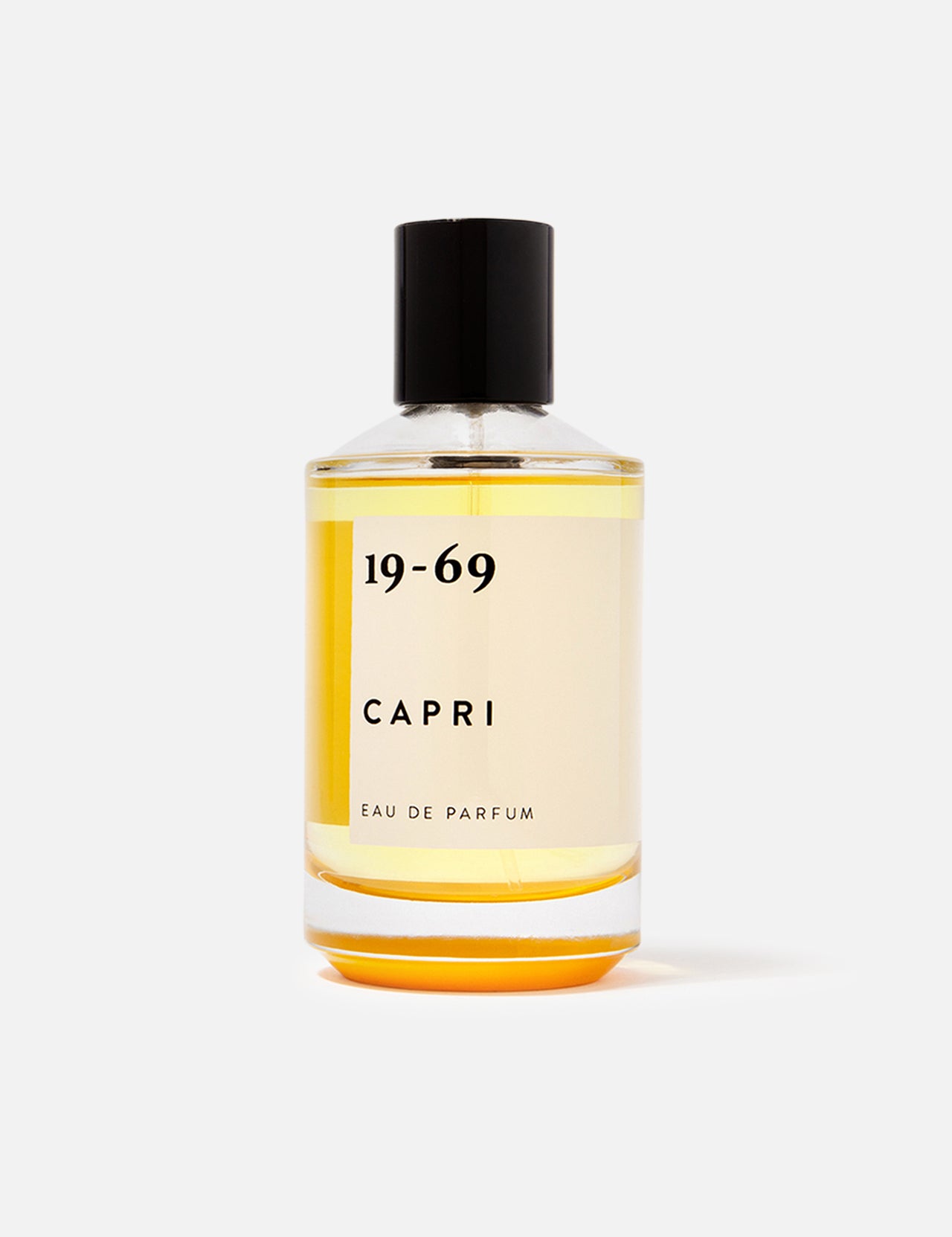 The 19-69 Capri EDP 100 ml Fragrance features a clear glass bottle with a black cap, filled with light yellow liquid. Displayed against a white background, this scent is inspired by Capri and highlighted by orange blossom notes.