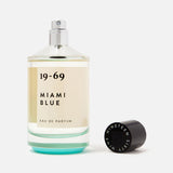 A clear glass bottle of 19-69 Miami Blu EDP 100 ml Fragrance, a fresh aquatic unisex scent, with a black "Nineteen Sixty Nine" cap beside it, set against a white background.