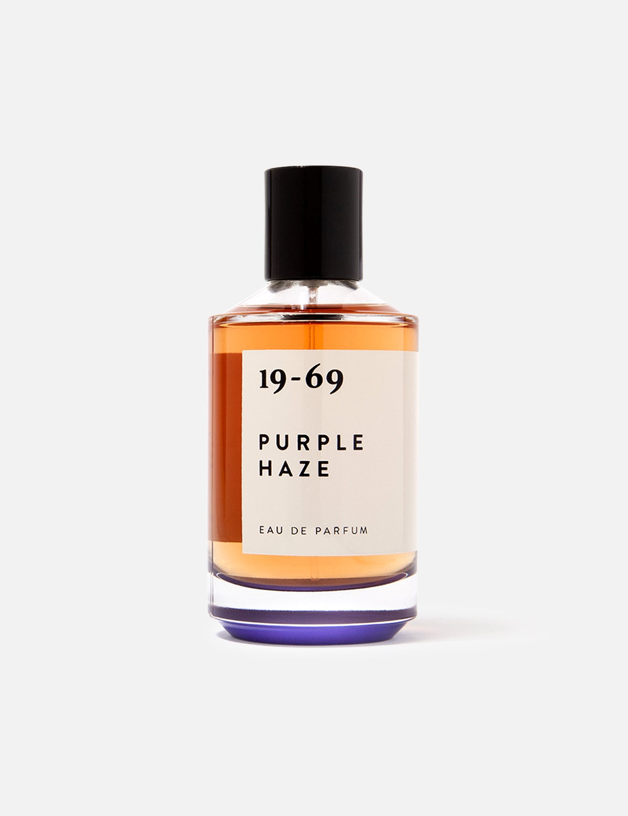 The 19-69 Purple Haze EDP 100 ml Fragrance is a Woodstock-inspired unisex scent in a clear glass bottle with amber liquid, black cap, and minimalist black-on-white label for a unique fragrance experience.