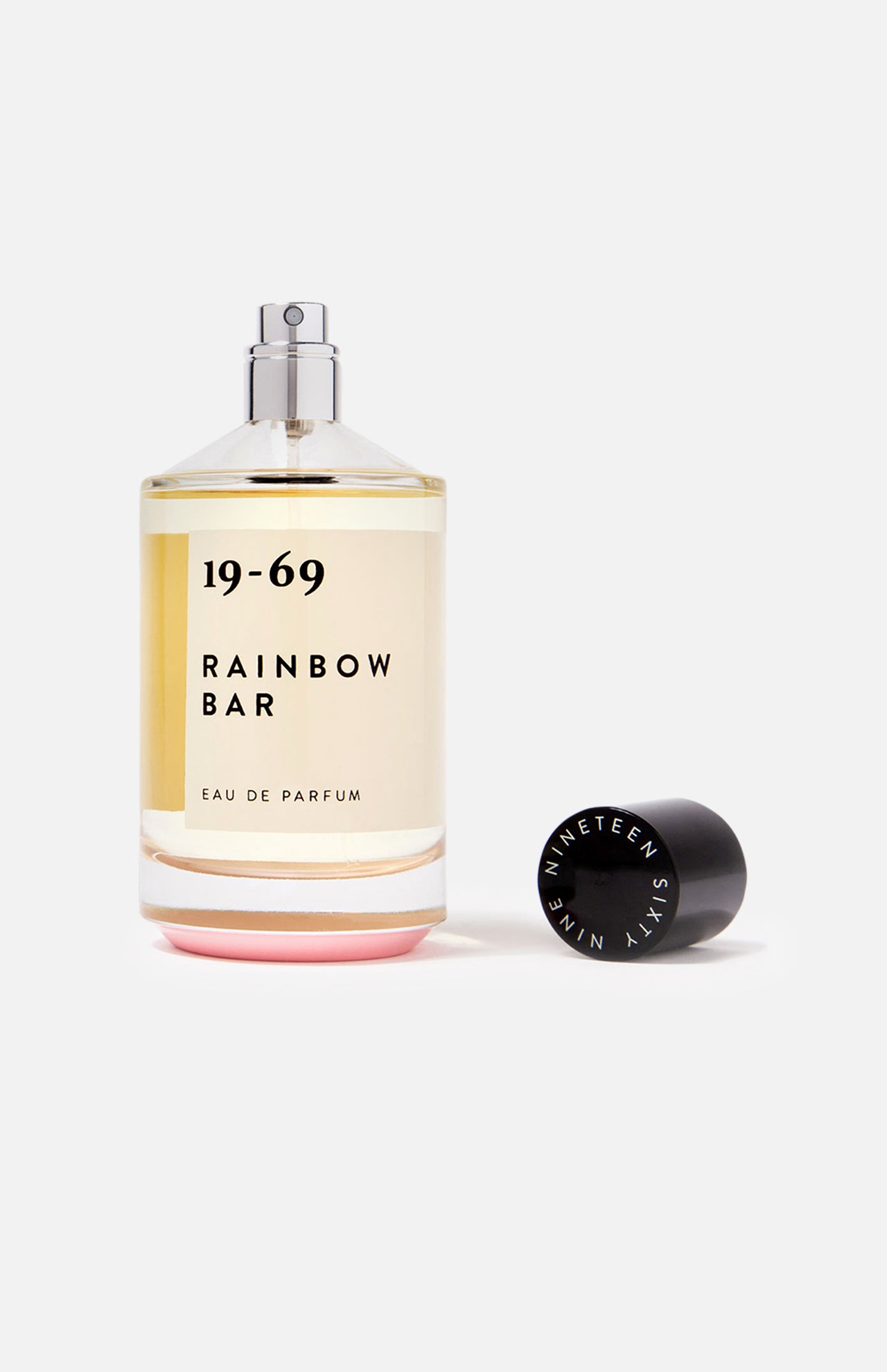 A clear 19-69 Rainbow Bar EDP 100 ml Fragrance bottle stands upright with its black cap, marked NINETEEN SIXTY NINE, beside it on a white background. This unisex perfume is inspired by the iconic Rainbow Bar scent.