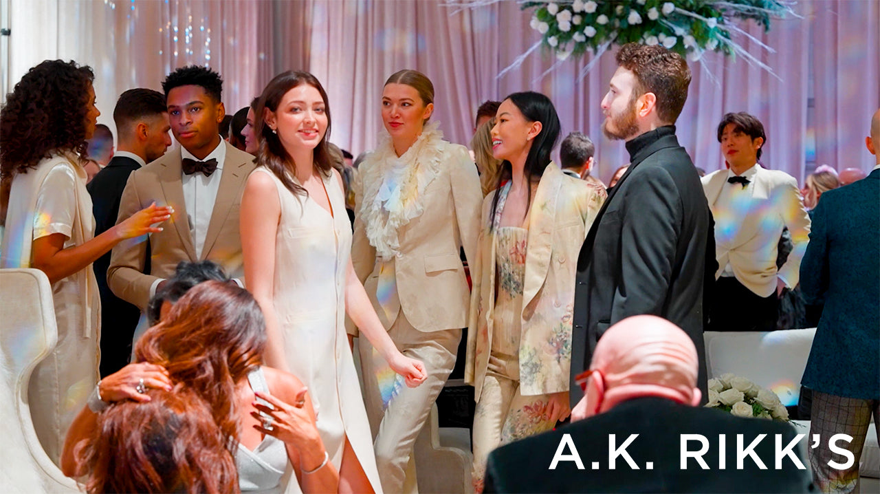 image with text "A.K. Rikk's" image is a wide shot of party goers dancing and chatting at a holiday party