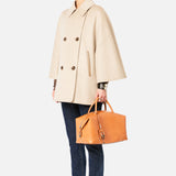 A person wearing a beige Max Mara Cashmere Button Sleeve Cape Jacket, dark jeans, and brown loafers, carrying a tan leather handbag.