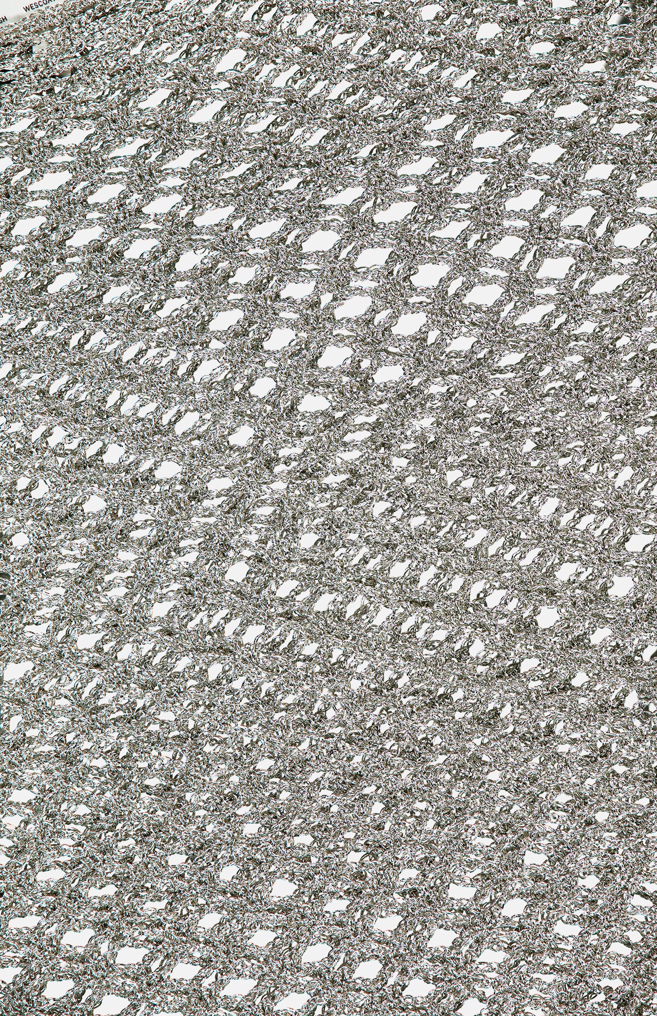 Close-up of the TWP Hand Crochet Slash Neck Top, showing its silver metallic mesh fabric with an open, net-like pattern and diagonal intertwined threads that let light filter through.
