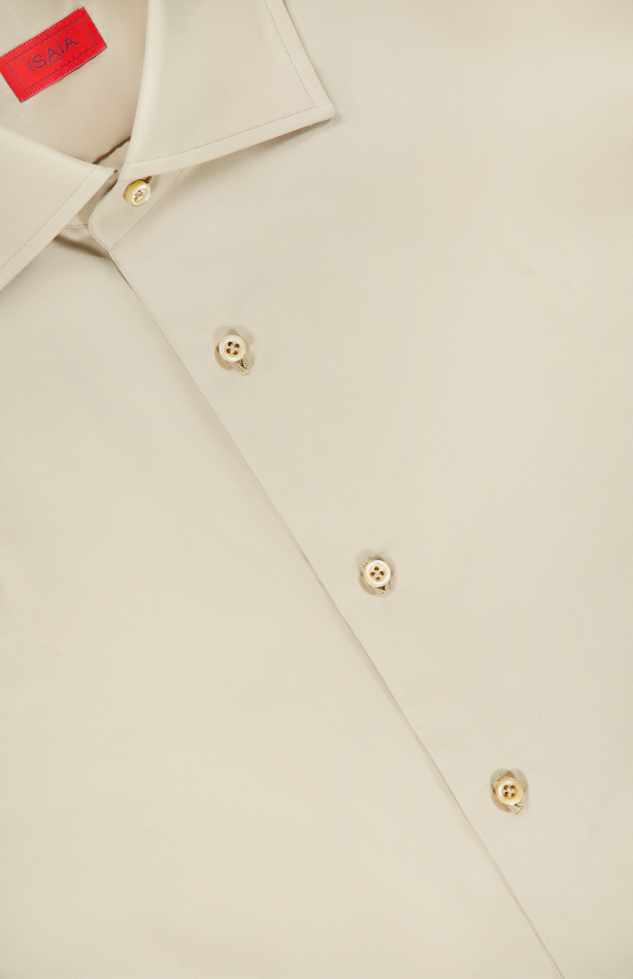 A close-up of the Tessuto Camicia Dress Shirt by ISAIA, featuring a beige fabric, cream-colored buttons, and a distinctive red ISAIA label on the inside collar—an elegant reflection of refined Italian style.