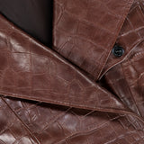 Close-up of the Jaxson Leather Moto Jacket from RALPH LAUREN COLLECTION, made of brown crocodile-patterned lambskin leather, highlighting its visible collar, lapel, and signature black button—an ode to the refined craftsmanship synonymous with Ralph Lauren.