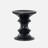 The Eames Turned Stool, Shape A by HERMAN MILLER is a small black hourglass-shaped stool with smooth sculptural lines and subtle textured patterns, inspired by the classic Eames walnut stool, shown on a plain light gray background.