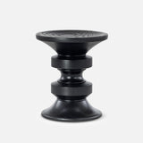 The HERMAN MILLER Eames Turned Stool, Shape D, is a modern black stool crafted from solid walnut, featuring a sculptural geometric design with rounded discs, ridged texture, and a slightly concave seat for lasting elegance.
