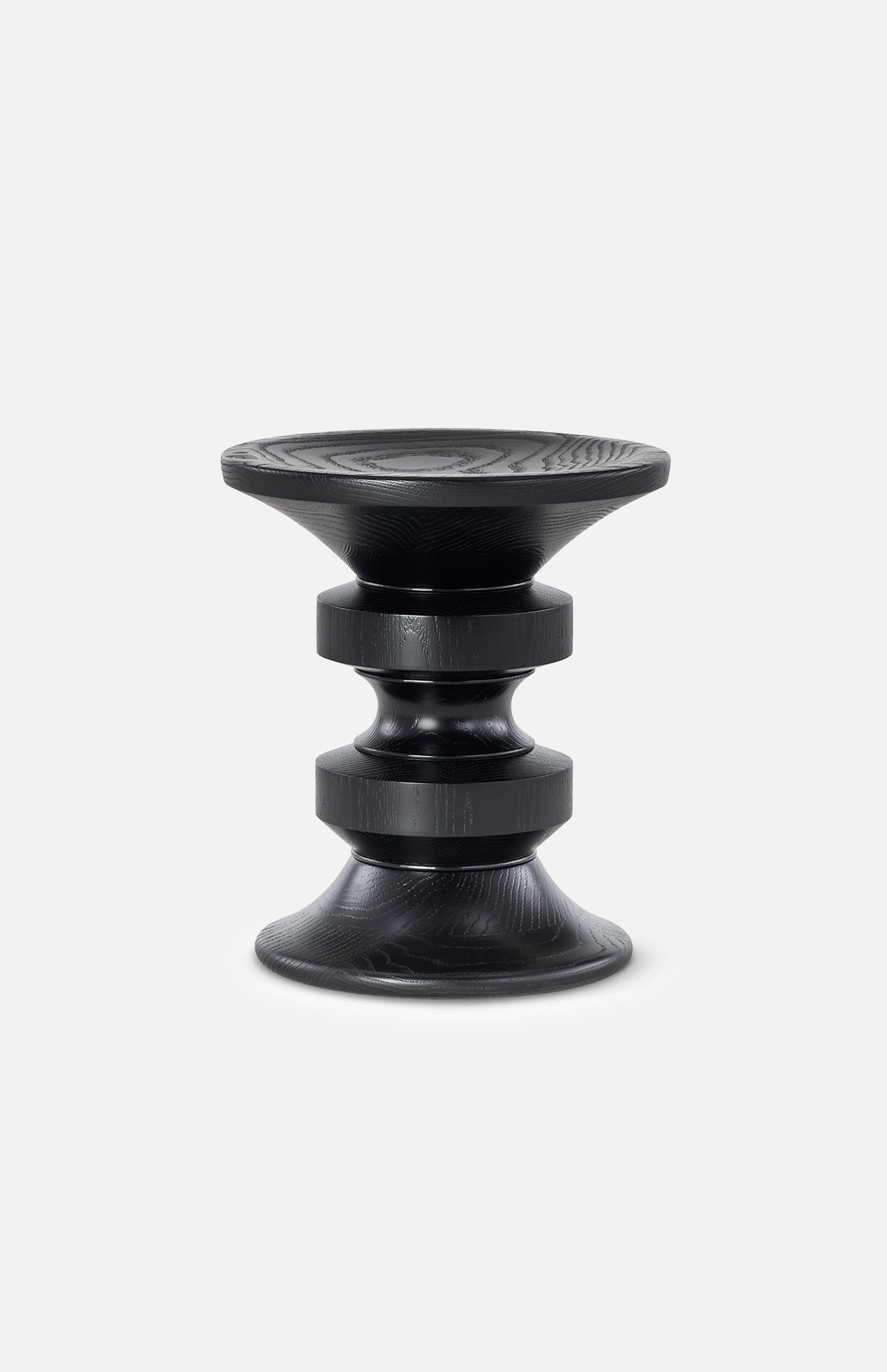 The HERMAN MILLER Eames Turned Stool, Shape D, is a modern black stool crafted from solid walnut, featuring a sculptural geometric design with rounded discs, ridged texture, and a slightly concave seat for lasting elegance.