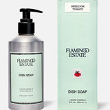 A bottle and box of FLAMINGO ESTATE Heirloom Tomato Dish Soap, both light green with black text. The box features a red tomato graphic, English details, and highlights a fresh tomato leaf scent with biodegradable cleansers.