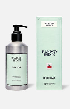 A bottle and box of FLAMINGO ESTATE Heirloom Tomato Dish Soap, both light green with black text. The box features a red tomato graphic, English details, and highlights a fresh tomato leaf scent with biodegradable cleansers.