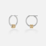 The Ara Deux Diamond Detail Earrings by SPINELLI KILCOLLIN are small sterling silver hoops featuring three gold rings as accents, shown on a plain white background.