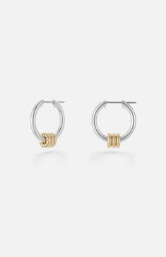 The Ara Deux Diamond Detail Earrings by SPINELLI KILCOLLIN are small sterling silver hoops featuring three gold rings as accents, shown on a plain white background.