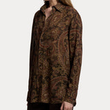 A person wearing the Paisley Collared Long Sleeve Blouse by RALPH LAUREN COLLECTION, featuring a relaxed fit and elegant brown and gold paisley print, paired with dark pants. The photo is cropped at the knees and does not reveal the full face—making it perfect inspiration for your fall wardrobe.