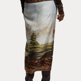 Back view of a RALPH LAUREN COLLECTION Scenic Silk Twill Pencil Skirt, a midi-length garment featuring a landscape print and leopard-print trim at the waistband and hem.