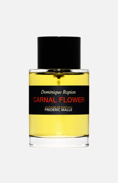 A clear glass bottle of yellow Carnal Flower Parfum 100ml by FREDERIC MALLE, with a black cap and a label displaying the brand and fragrance name in white, red, and gold text.