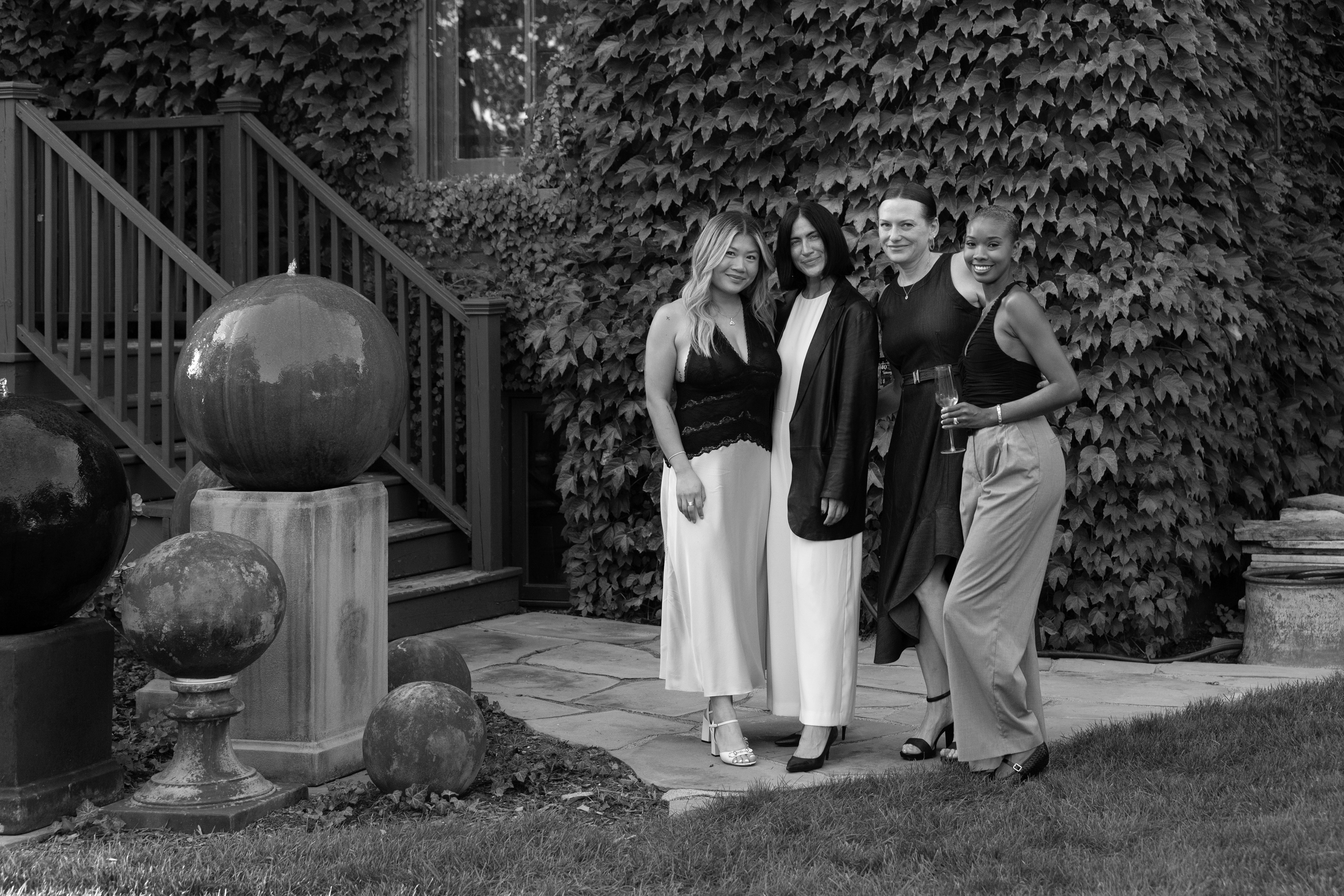 Four women standing together outdoors with decorative elements in the background