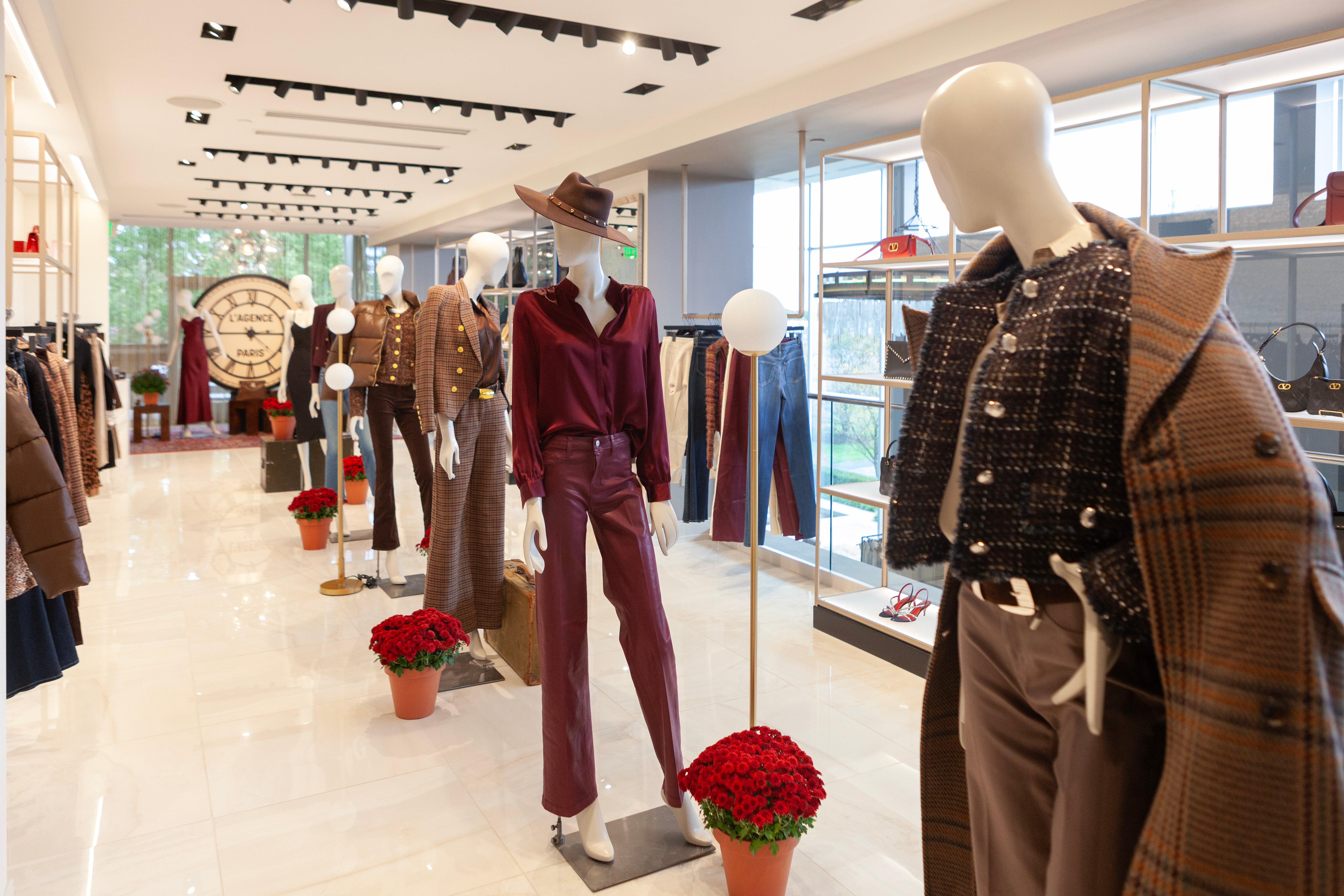 Mannequins dressed in winter clothing in a store setting with decorative flowers.