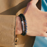 A close-up of a wrist adorned with the TATEOSSIAN Vintage Herringbone Click Bracelet, paired with a beaded black and blue bracelet, worn with a beige jacket for a refined men's luxury look.