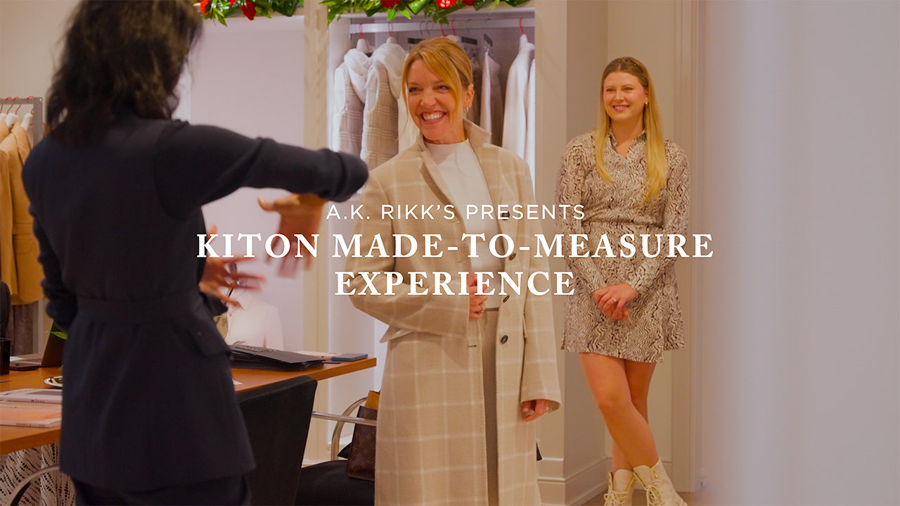 image with text "A.K. Rikk's Presents Kiton Made-To-Measure Experience" image is of a woman wearing a beige top coat while shopping at A.K. Rikk's 