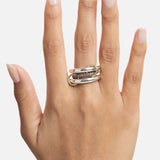 A hand with natural, neatly manicured nails wears the SPINELLI KILCOLLIN Libra Gris Diamond Ring—a chunky double-band design in sterling silver and gold with sparkling diamonds—on the middle finger against a white background.