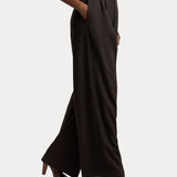 A person wearing the RALPH LAUREN COLLECTION Mini Herringbone Standard Pants in a relaxed, wide-leg fit and heeled brown ankle boots, with hands in pockets, shown from the waist down.