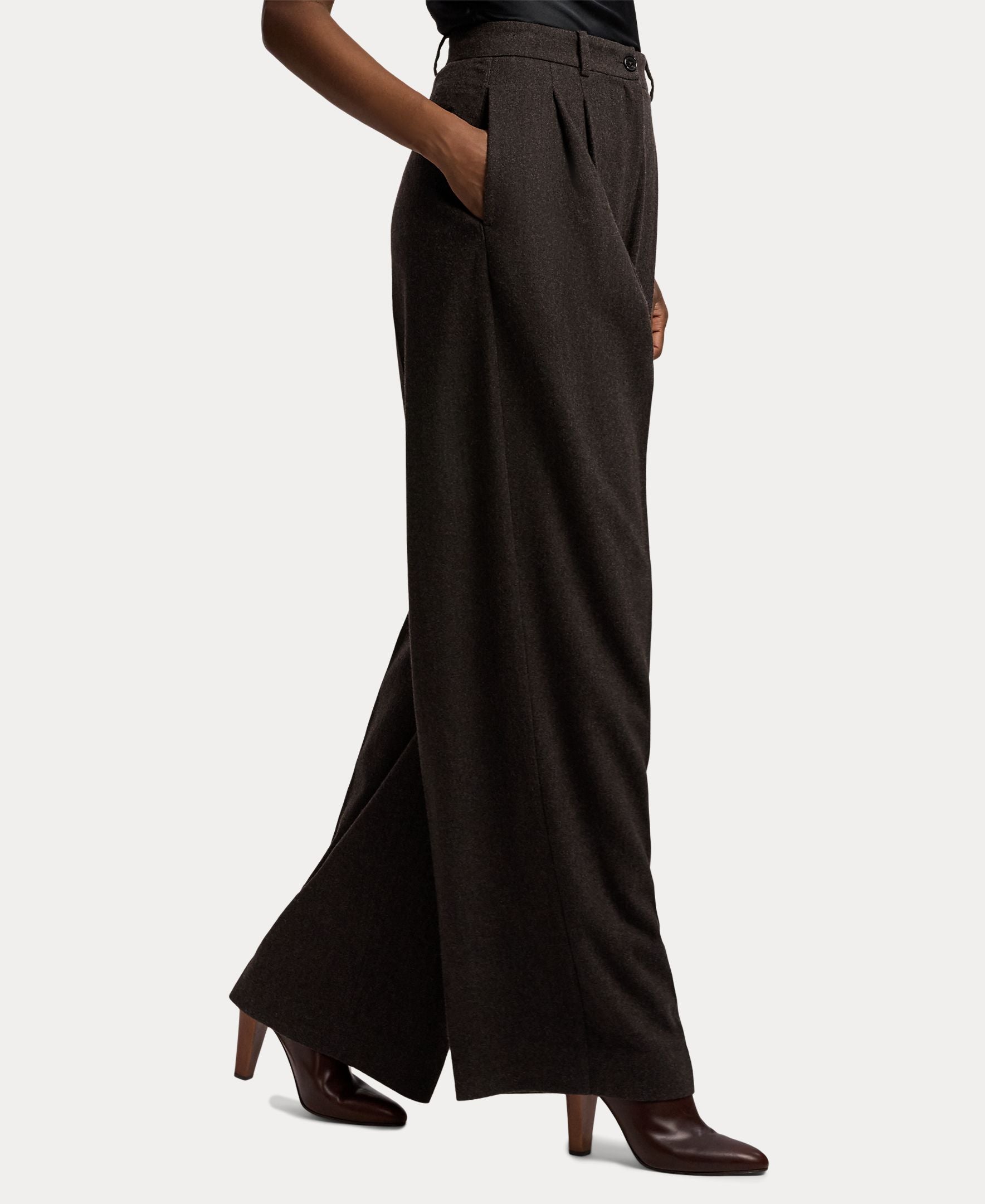 A person wearing the RALPH LAUREN COLLECTION Mini Herringbone Standard Pants in a relaxed, wide-leg fit and heeled brown ankle boots, with hands in pockets, shown from the waist down.