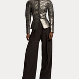 A person wearing a metallic silver fitted jacket with long sleeves and structured shoulders, paired with RALPH LAUREN COLLECTION Mini Herringbone Standard Pants in a dark brown suiting fabric and brown heeled shoes. The background is plain white.