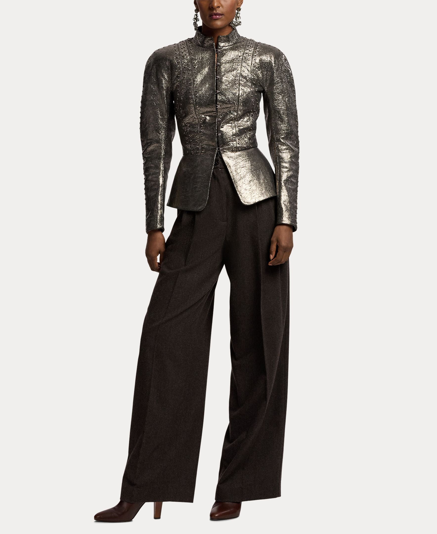 A person wearing a metallic silver fitted jacket with long sleeves and structured shoulders, paired with RALPH LAUREN COLLECTION Mini Herringbone Standard Pants in a dark brown suiting fabric and brown heeled shoes. The background is plain white.