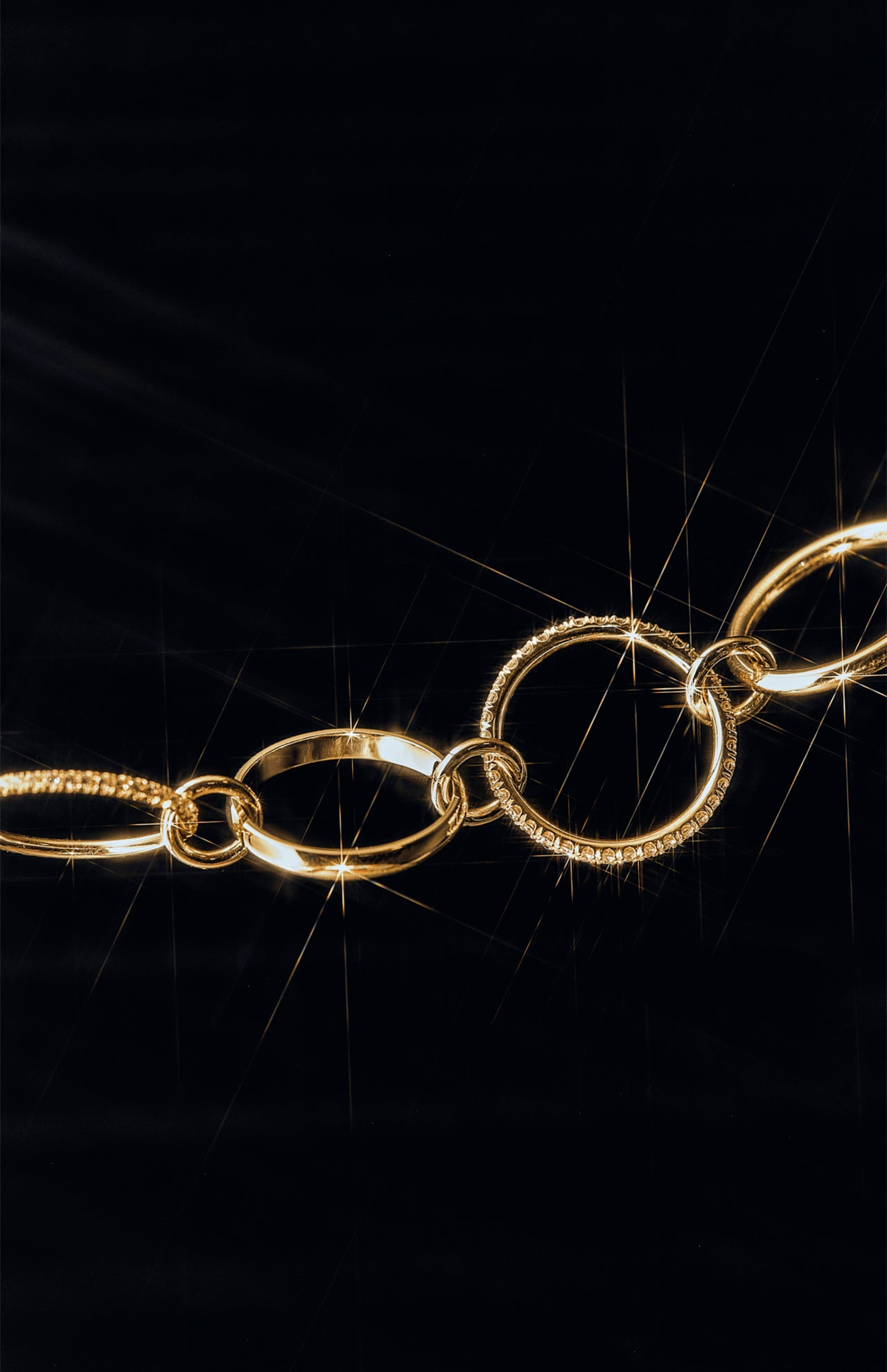 A close-up of the Polaris 4 Band Ring by SPINELLI KILCOLLIN, its circular bands gleaming against a black background for a luxurious, elegant effect reminiscent of modular jewelry.