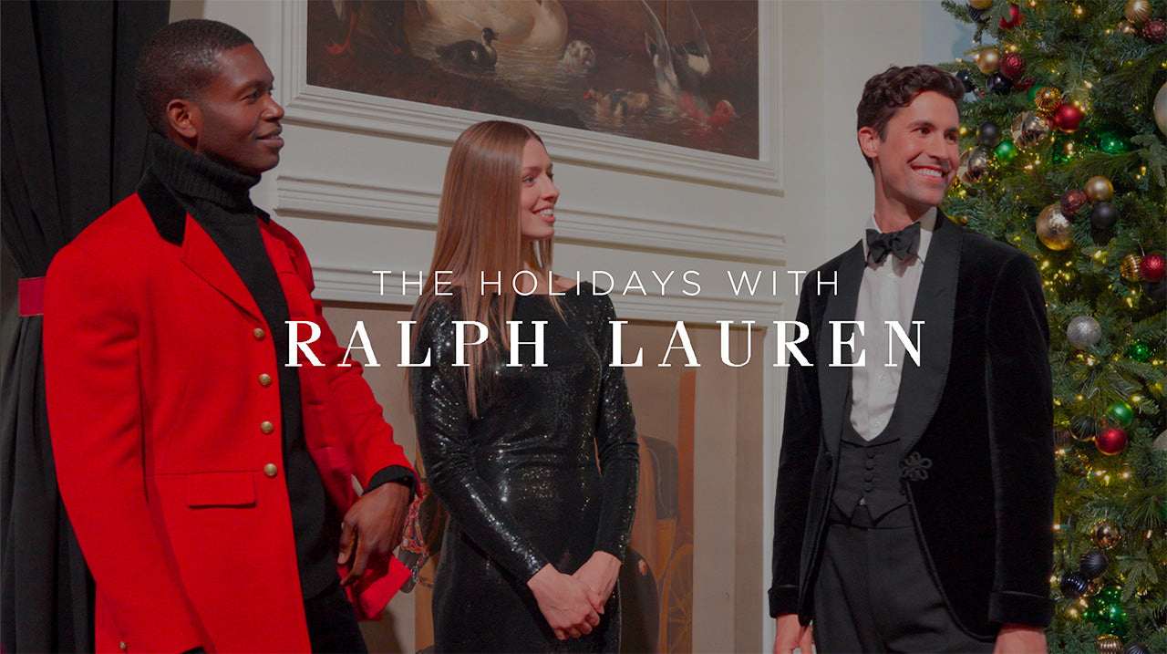 image with text "The Holidays with Ralph Lauren" image is of models wearing Ralph Lauren mingling with one another next to a fireplace and Christmas tree